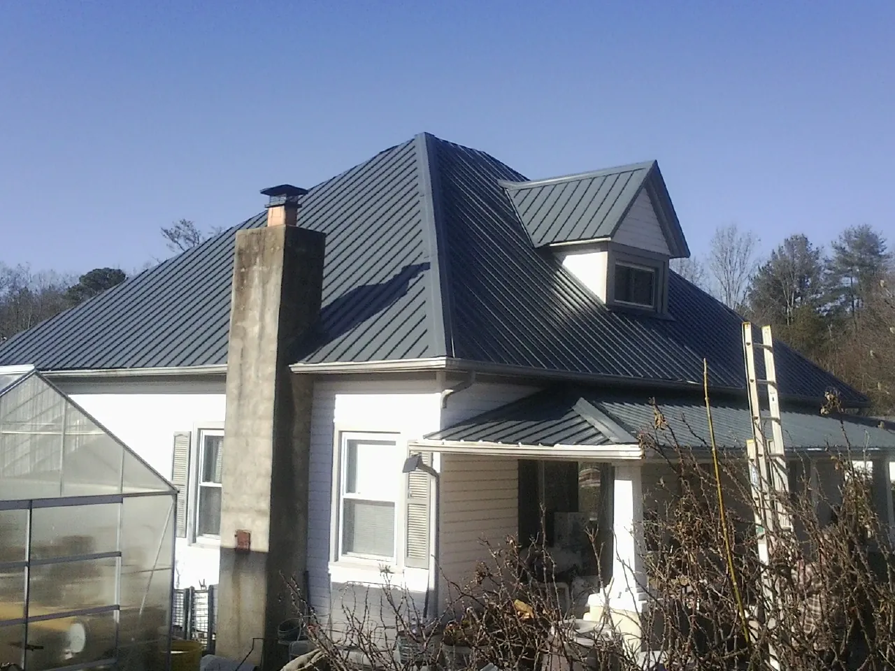 Dark blue standing seam metal roof on a white farmhouse with dormer — Slate & Tile Roof Repair by Roofing Brothers in Gardners
