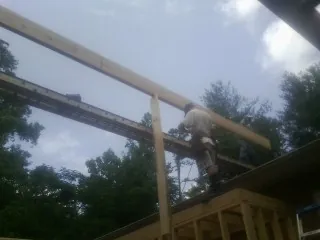Carpenter setting a ridge beam over a new addition frame — Ice Dam Removal by Roofing Brothers in Gardners