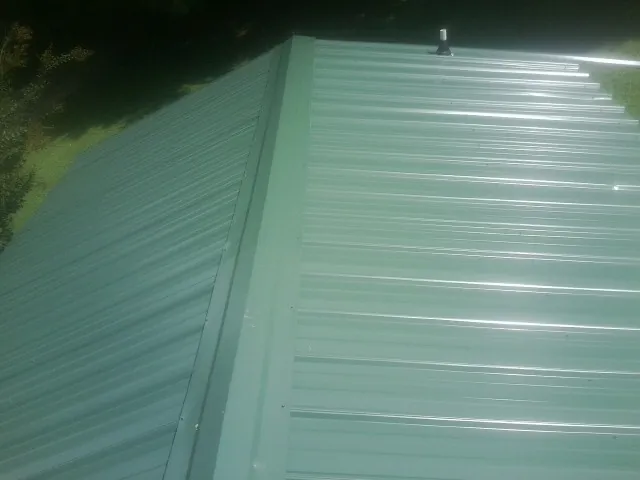 New green metal panels meeting at the ridge of a roof — Flat Roof Repair work by our crew in Gardners