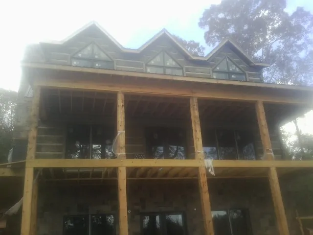 Dormers and porch framing on a large log home under construction — Roof Coating work by our crew in Gardners