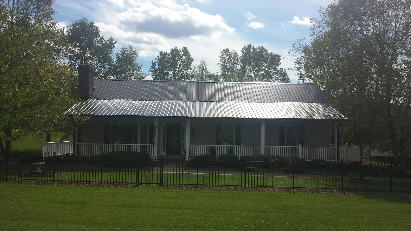 Gray metal roof on a brick ranch with a full width front porch — Gutter Guard Installation work by our crew in Gardners