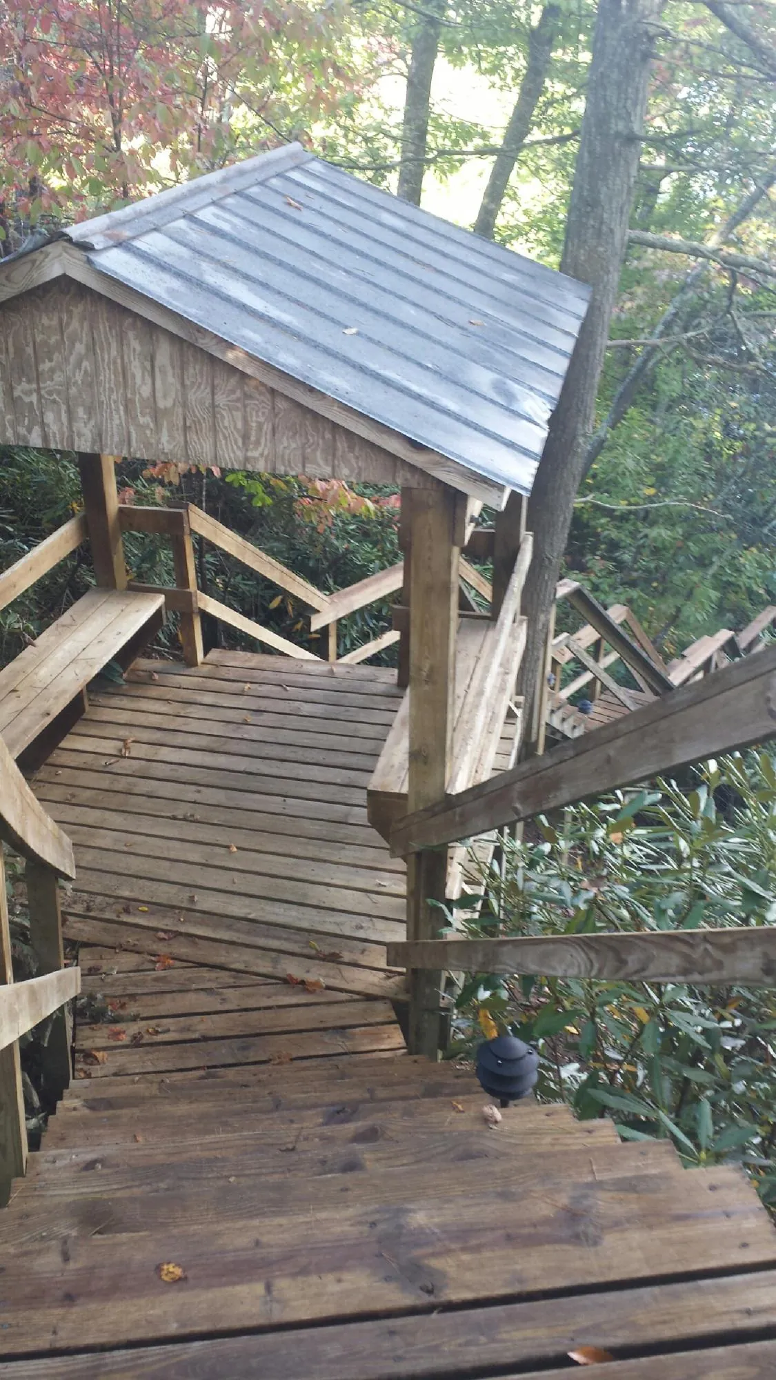 Metal roofed shelter over wooden steps on a wooded walkway — Skylight Repair & Installation work by our crew in Gardners