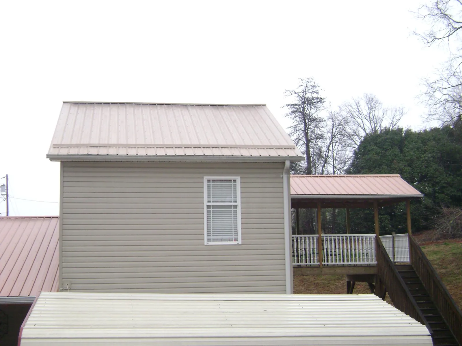 Tan metal roofs on a two story addition and attached porch, from a Roof Replacement job in Gardners