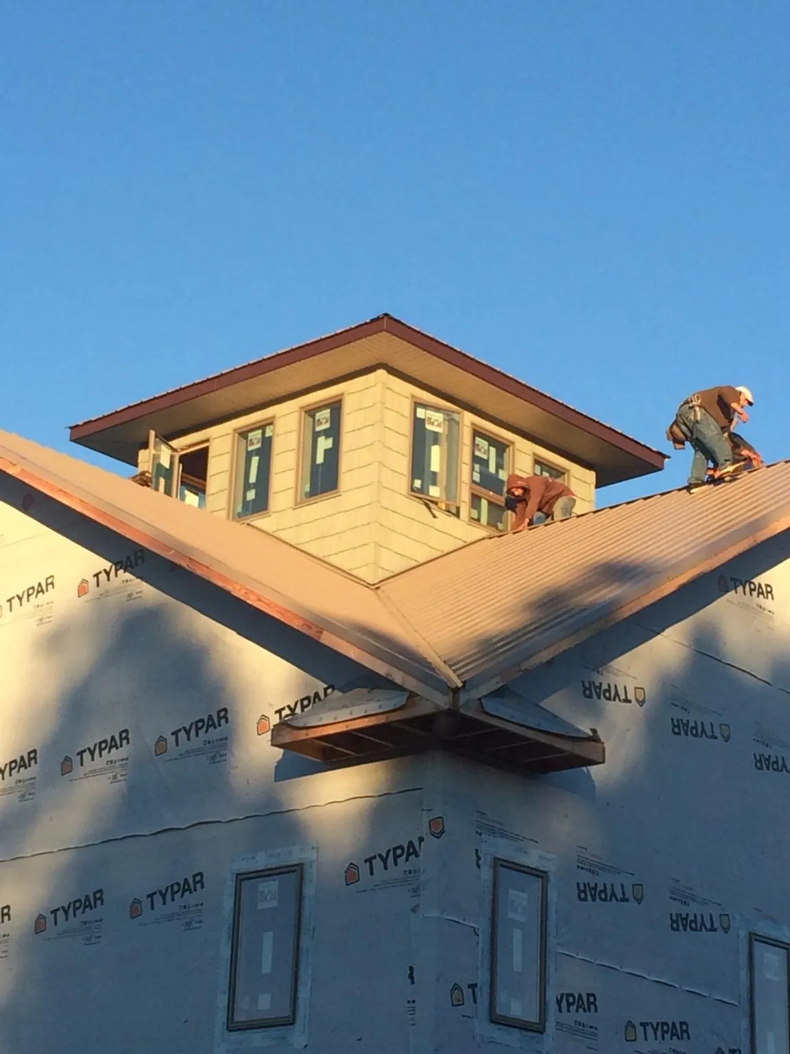 Roofers working around a rooftop cupola on a new metal roof at sunset — Roof Waterproofing in Gardners by Roofing Brothers